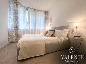 Dormitorio blanco con cama y ventana en Casa al Mare - Torre del Lago- Valente Italian Properties, en Torre del Lago Puccini