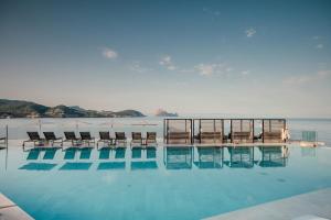 a swimming pool with chairs and the ocean in the background at 7Pines Resort Ibiza, part of Destination by Hyatt in San Jose