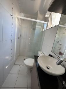 a white bathroom with a sink and a toilet at Edificio Long Beach in Balneário Camboriú