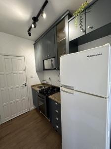 a kitchen with a white refrigerator and a stove at Edificio Long Beach in Balneário Camboriú