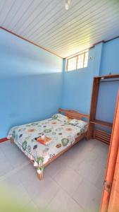 Cama pequeña en habitación con pared azul en Residencia Grecia, en Leticia