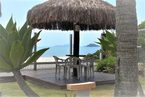 um deque com 2 cadeiras, uma mesa e um guarda-sol de palha em Pousada Holiday em Florianópolis