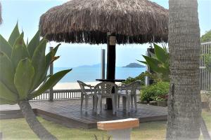 a deck with two chairs and a table and a straw umbrella at Pousada Holiday in Florianópolis