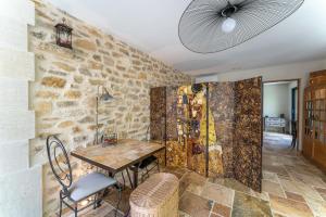 ein Esszimmer mit einem Tisch und einer Steinmauer in der Unterkunft Villa La Mireio in Malaucène