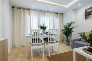 GENESIS APARTMENT IN MADRID في مدريد: غرفة معيشة مع طاولة وكراسي بيضاء