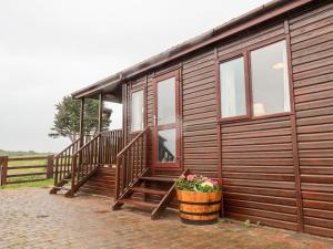 a wooden cabin with stairs and a pot of flowers at Handale Banks Farm Lodge in Saltburn-by-the-Sea