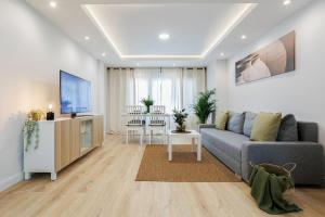 GENESIS APARTMENT IN MADRID في مدريد: غرفة معيشة مع أريكة رمادية وطاولة