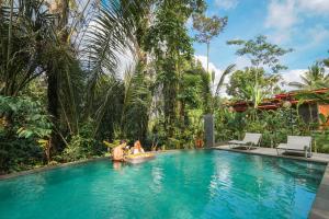 two people sitting in a bath tub in a swimming pool at Daydream Lodge in Tampaksiring