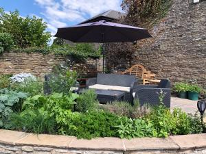 a patio with chairs and an umbrella in a garden at The Temple Bar Inn in Hereford