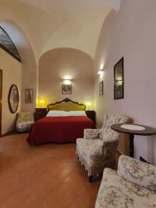 een slaapkamer met een bed en 2 stoelen en een tafel bij Palazzo Rustici b&b & apartments in LʼAquila