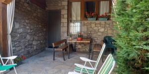 un patio con sillas, una mesa y una pared de piedra en El Torreón I, en Hoyos del Espino