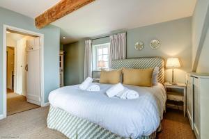 Un dormitorio con una gran cama blanca con dos almohadas. en Church End Cottage, en Swerford