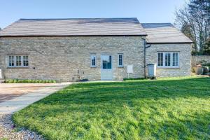 a brick house with a grass yard in front of it at Dairy Lodge in Bladon