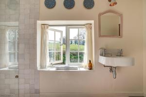 Un baño con lavabo y ventana. en Church End Cottage, en Swerford 27 fotos más