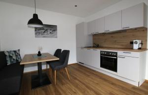 a kitchen with white cabinets and a table with chairs at Apart Christoph in Oetz