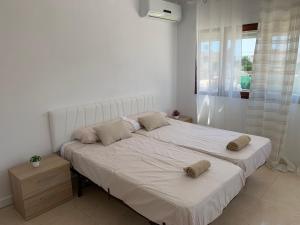 a bedroom with a large white bed with two pillows on it at Casa los Pinos Calpe Playa in Calpe