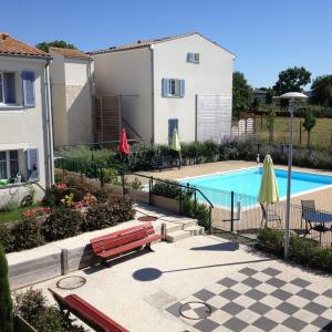 una casa y una piscina con un banco y sombrillas en Résidence services Les Essentielles Sainte Soulle, en Sainte-Soulle