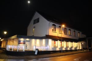 un edificio blanco con luces de Navidad encendidas por la noche en Hotel Aulum Kro en Avlum