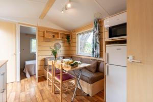 une petite cuisine et une salle à manger dans une petite maison dans l'établissement Le Photinia, mobil-home climatisé avec vue mer situé au cœur du domaine, à Hyères