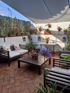 un patio con sofás, mesas y macetas en La Gitanilla Alojamiento & Encanto Jerez en Jerez de la Frontera