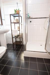 a bathroom with a shower and a black tile floor at Cute Beach House Zandvoort in Zandvoort