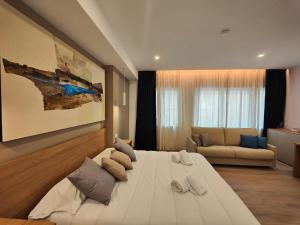 un grande letto bianco in una camera con divano di Carducci Art Guesthouse a Oristano