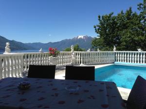 a table and chairs next to a swimming pool at Romantic holiday home with a fantastic view of Lake Maggiore and the pool in Gordola