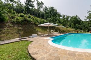 uma piscina com um guarda-sol ao lado de uma colina em Pugnano Alto - appartamento Grano em Lisciano Niccone