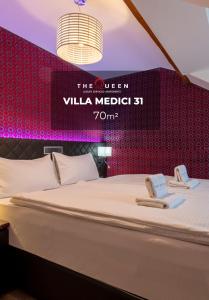 a bed in a room with a sign that reads the queen villa medici at The Queen Luxury Apartments - Villa Medici in Luxembourg
