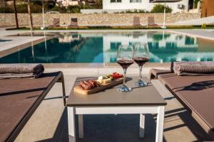 two glasses of wine on a table next to a pool at Kayy Apartments 4 in Matala in Matala