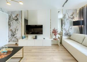 sala de estar con sofá blanco y TV en A&J APARTS GDYNIA en Gdynia
