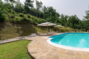 a swimming pool with an umbrella next to a hill at Pugnano Alto -appartamento Castagna in Lisciano Niccone