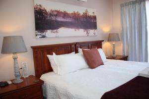1 dormitorio con 1 cama con sábanas y almohadas blancas en Accommodation at Potch Guesthouse, en Potchefstroom