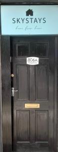 Una puerta negra con un cartel. en The King Stay, en Mánchester