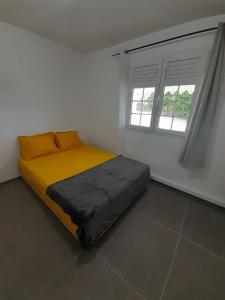 een bed in een witte kamer met 2 ramen bij Maison ika in Le François
