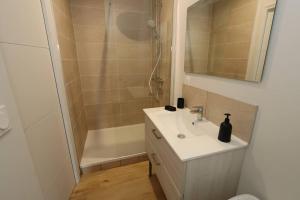 a white bathroom with a sink and a shower at Maison Charme & Mer à Dunkerque in Dunkerque