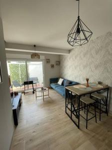 a living room with a table and a blue couch at Maison Charme & Mer à Dunkerque in Dunkerque