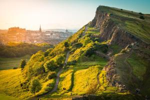 a view of a mountain with a city in the background at The Holyrood Park Apartment in Edinburgh