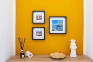 a yellow wall with four framed pictures on it at Labiena Lake Maggiore in Laveno