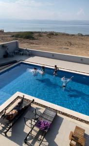 a group of people swimming in a swimming pool at Follow Sea Villa in Sowayma