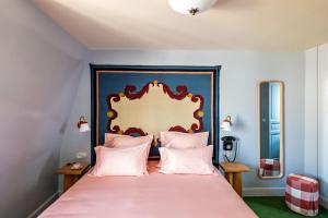 a bedroom with a pink bed with a blue headboard at Hôtel de La Boétie in Paris
