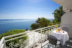 a balcony with a table and chairs and the ocean at Hotel Stanger in Lovran
