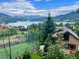 a tennis court on a hill next to a lake at VIP Villa & Spa in Colibiţa