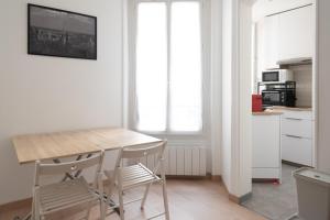 uma cozinha com uma mesa de madeira e cadeiras num quarto em Very bright nest close to Belleville park em Paris