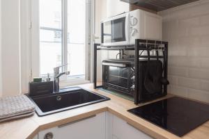 a kitchen with a sink and a microwave at Very bright nest close to Belleville park in Paris