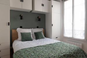 um quarto com uma cama com duas almofadas verdes em Very bright nest close to Belleville park em Paris