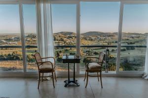 dwa krzesła i stół w pokoju z oknami w obiekcie Amaike Hotel Golf & Spa w mieście Tandil