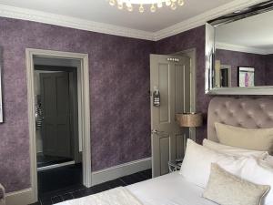 a bedroom with purple walls and a bed with a mirror at the kingsbury 7even 8ight in Marlborough