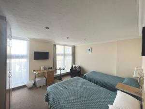 a hotel room with two beds and a desk at Eastbourne Riviera Hotel in Eastbourne