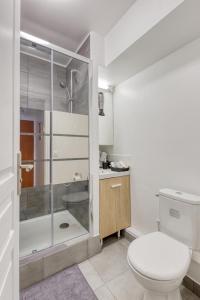 a white bathroom with a toilet and a shower at L'Appartement d'Art et de Lumière in Clichy